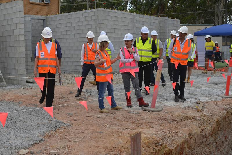 A group of bric & Queensland Government representatives are on a building site